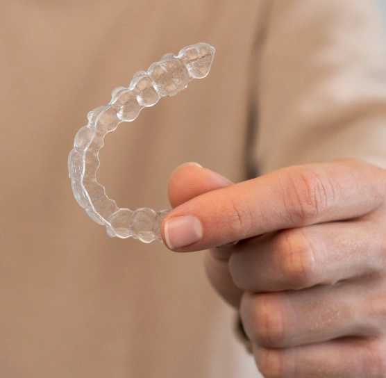 Clear aligner tray held by a patient at Ro Dental Group in Calgary, Alberta, showcasing a discreet orthodontic solution for straightening teeth.