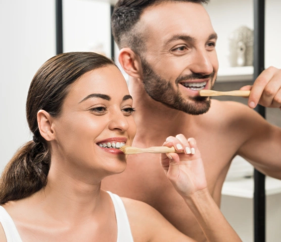 Two patients brushing their teeth together during their dental hygiene routine at Ro Dental Group in Calgary, AB.