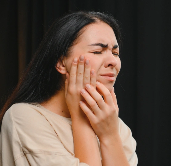 Woman experiencing TMJ disorder symptoms and jaw tension before seeking treatment at Rō Dental Studio in Calgary
