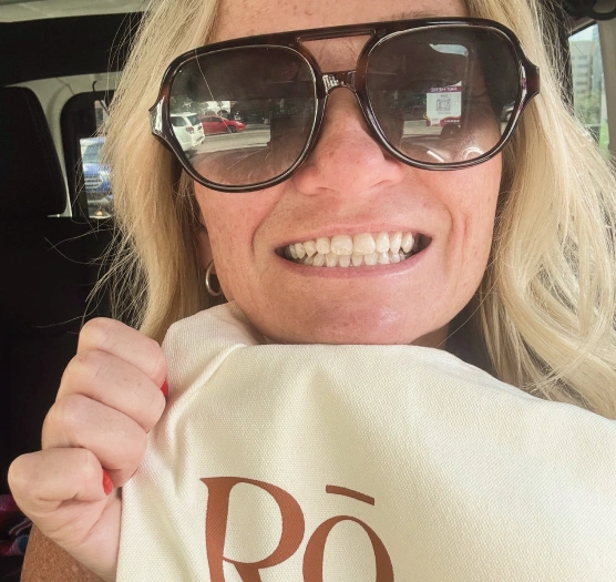 Smiling patient holding a Ro Dental Studio tote bag, reflecting the welcoming, patient-first dental experience at Ro Dental Studio in Calgary, AB.