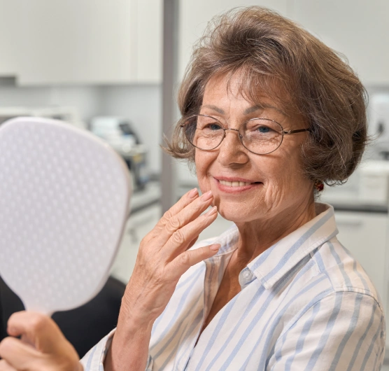 Injectable treatment patient admiring her smooth skin and facial aesthetic results at Rō Dental Studio in Calgary